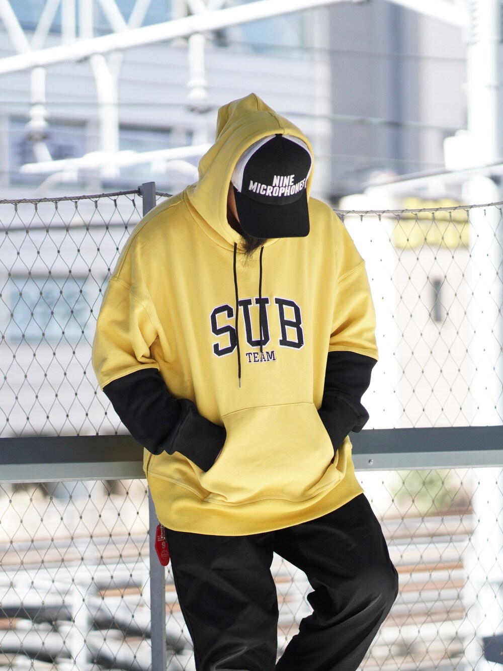 イエロー系のパーカー、ホワイト系のキャップを着用したメンズの冬コーディネートの1枚目の写真