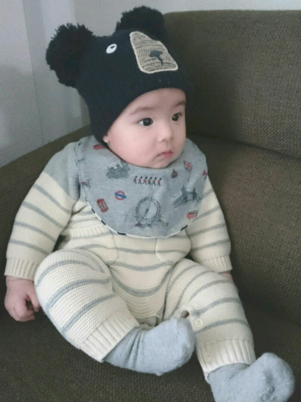 グレー系のスタイ/よだれかけ、ブラック系のニットキャップ/ビーニー、グレー系のロンパースを着用したキッズの冬コーディネートの1枚目の写真