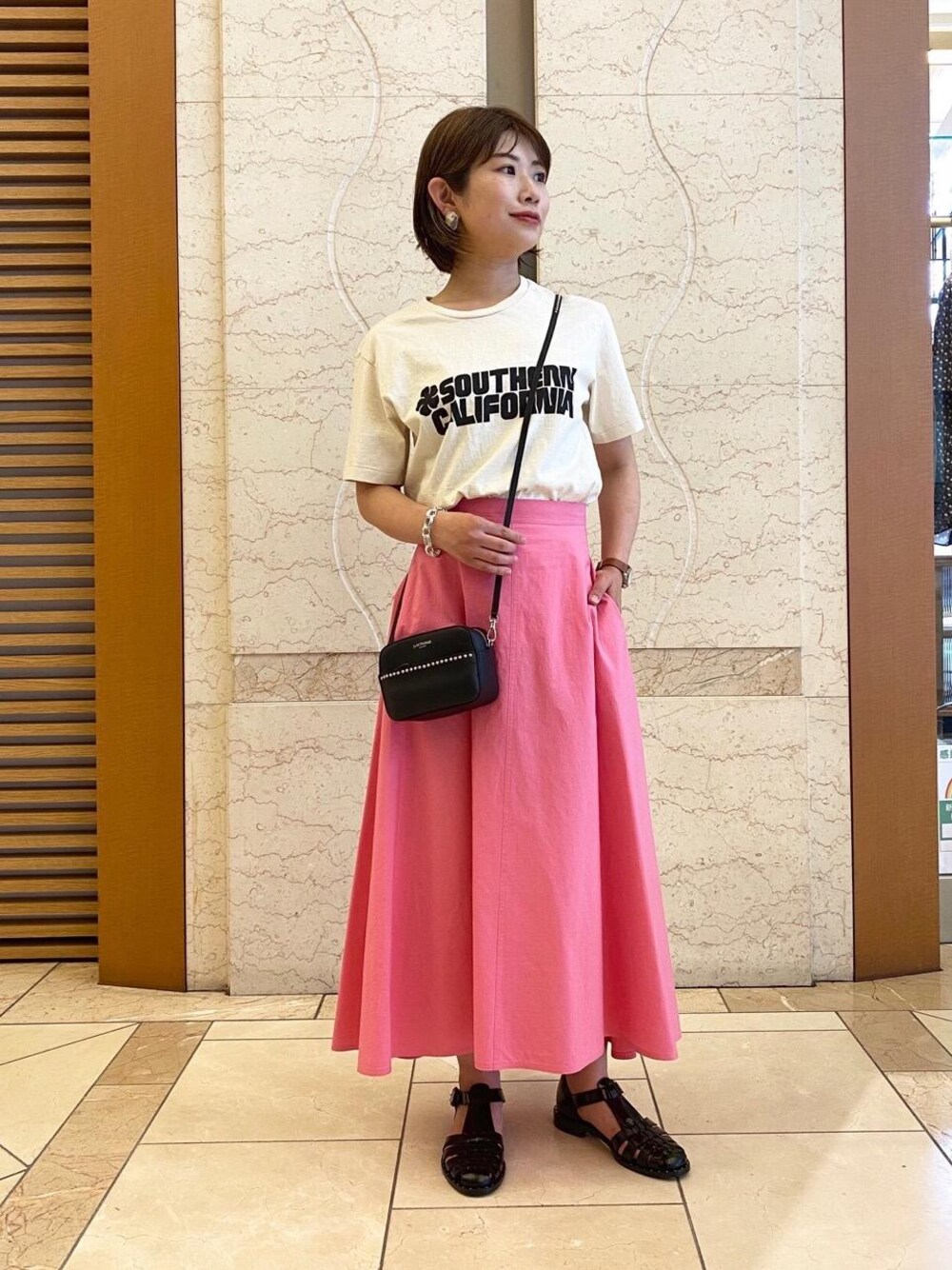 ホワイト系のTシャツ/カットソー、ブラック系のサンダル、シルバー系のブレスレットを着用したレディースの春コーディネートの1枚目の写真