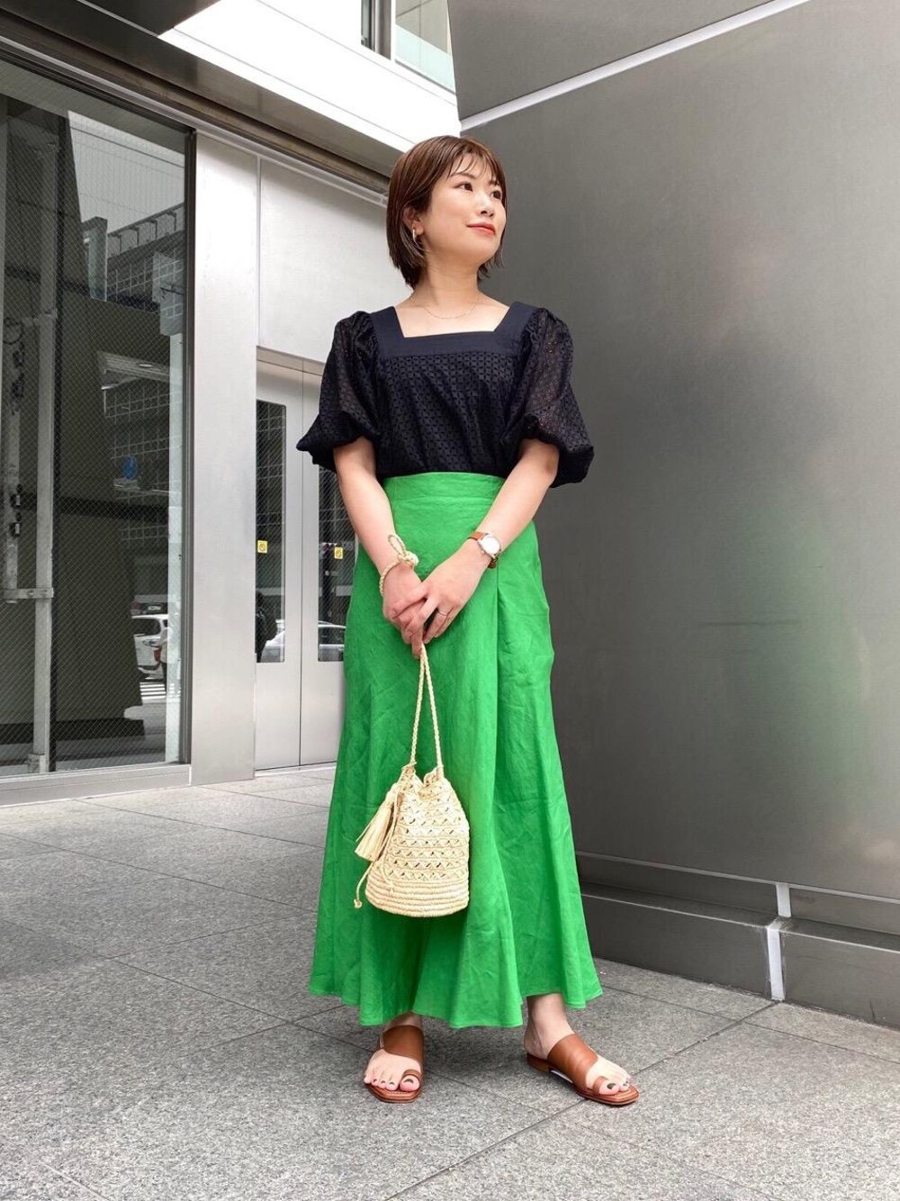 ブラウン系のサンダル、グリーン系のスカート、ホワイト系のショルダーバッグを着用したレディースの春コーディネートの1枚目の写真