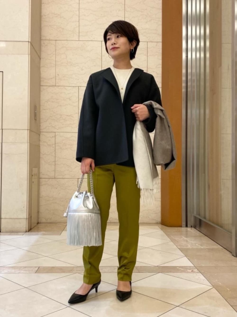 ブラック系のパンプス、ホワイト系のニット/セーター、グリーン系のその他パンツを着用したレディースの秋コーディネートの1枚目の写真