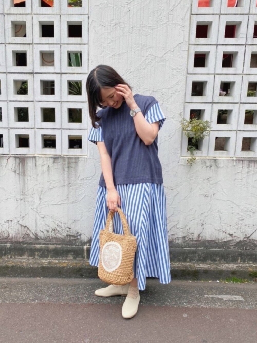グレー系のニット/セーター、ブルー系のワンピース、ベージュ系のトートバッグを着用したレディースの春コーディネートの1枚目の写真