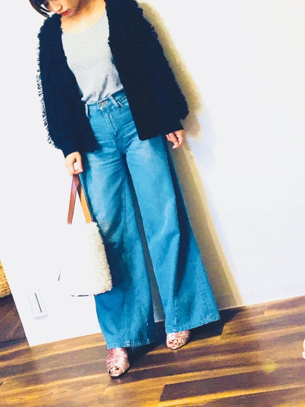 ブルー系のデニムパンツ、ホワイト系のハンドバッグ、グレー系のタンクトップを着用したレディースの秋コーディネートの1枚目の写真