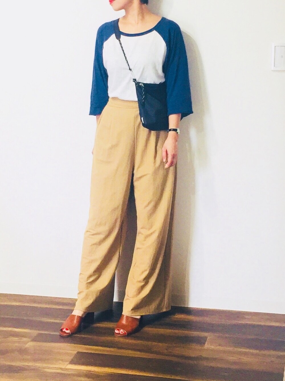 ブルー系のTシャツ/カットソー、ブラック系のショルダーバッグ、ベージュ系のパンツを着用したレディースの春コーディネートの1枚目の写真