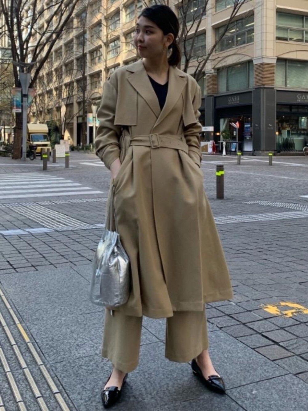 ベージュ系のその他パンツ、ベージュ系のトレンチコート、シルバー系のショルダーバッグを着用したレディースの冬コーディネートの1枚目の写真