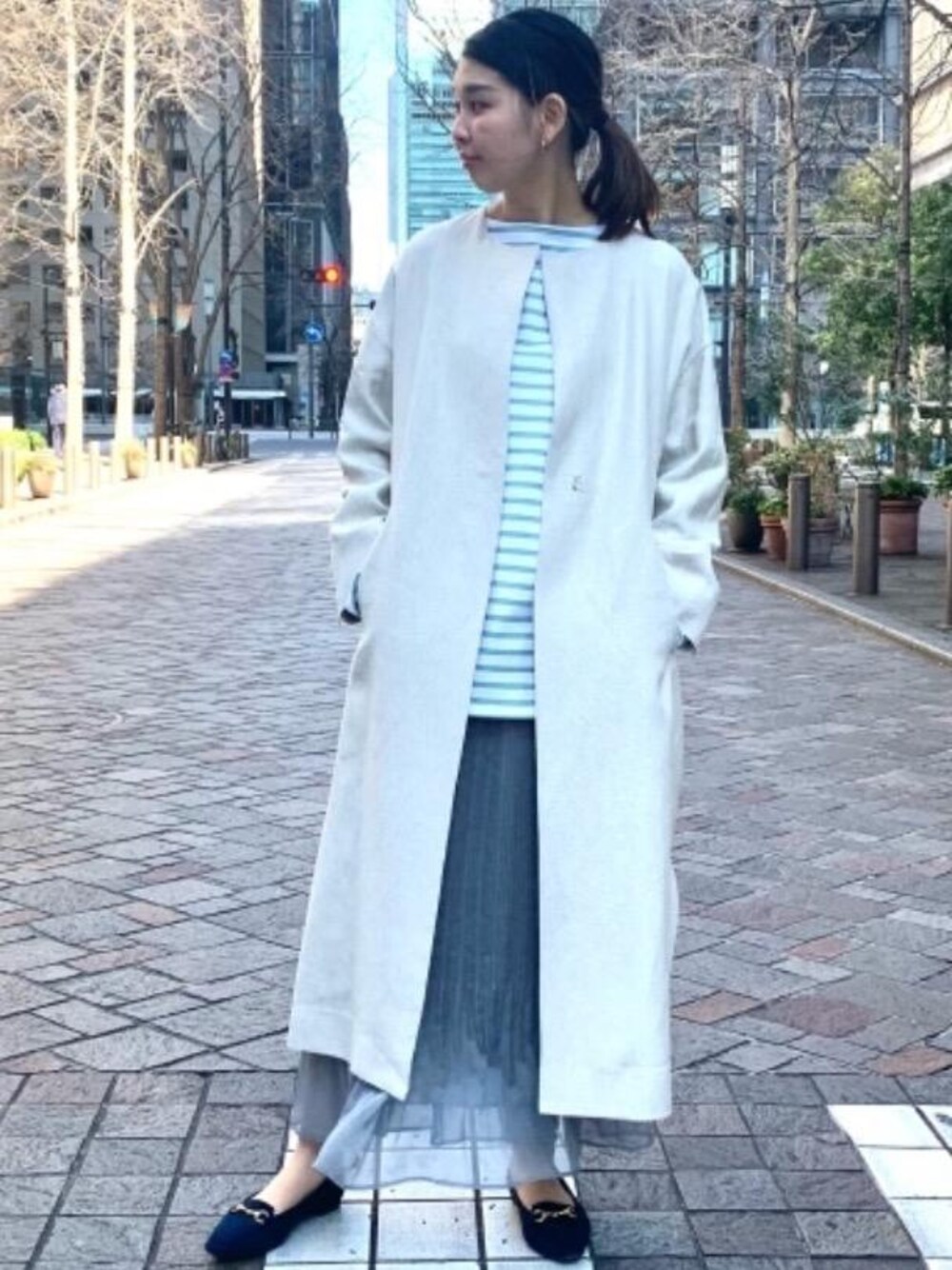 グリーン系のTシャツ/カットソー、ベージュ系のノーカラーコート、ブルー系のローファーを着用したレディースの冬コーディネートの1枚目の写真