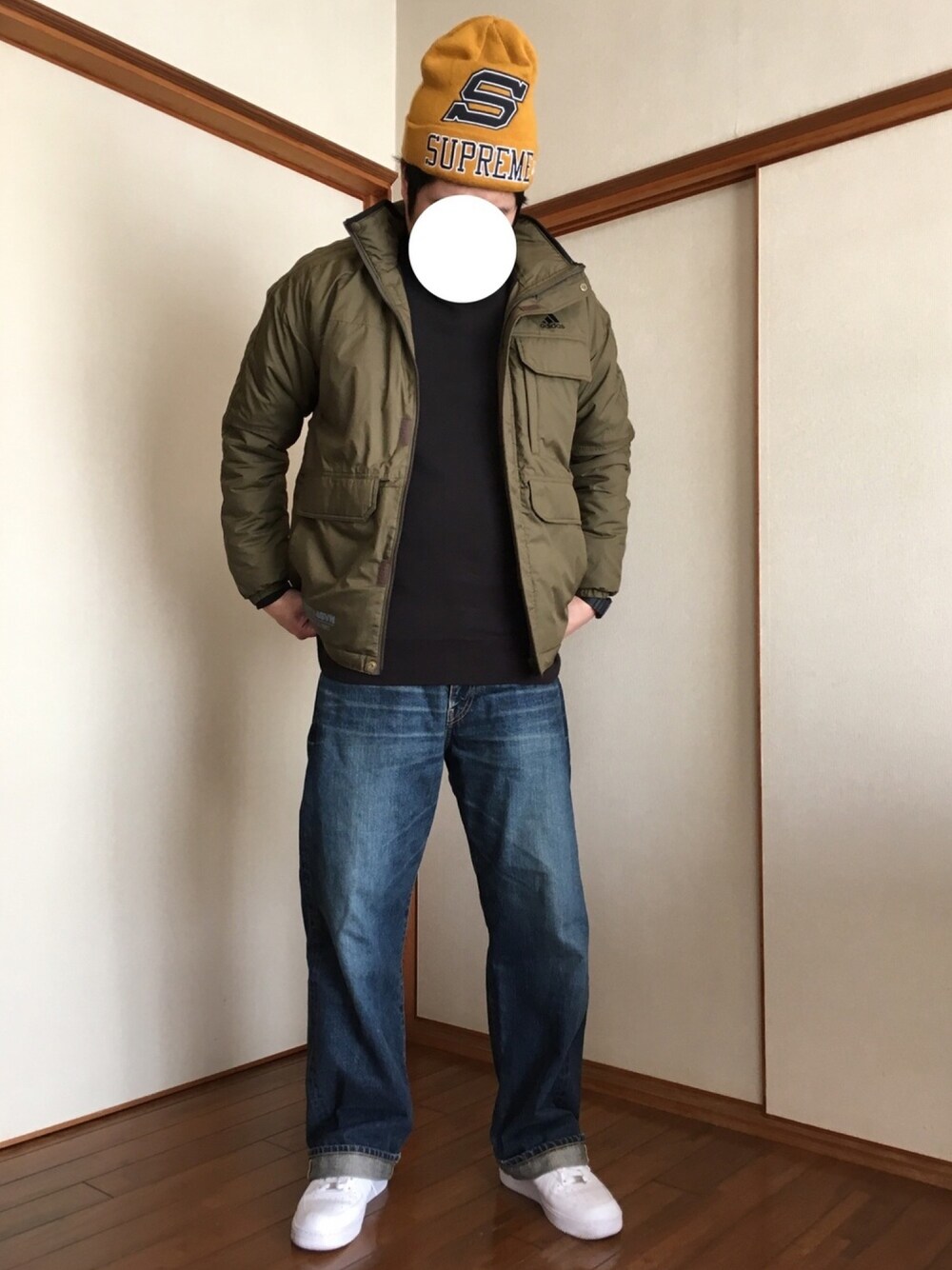 ホワイト系のスニーカー、ブルー系のデニムパンツ、グリーン系のナイロンジャケットを着用したメンズの秋コーディネートの1枚目の写真