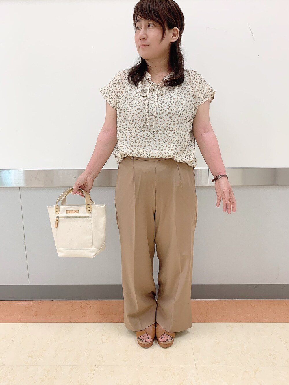 ベージュ系のパンツ、ベージュ系のトップス、ホワイト系のトートバッグを着用したレディースの夏コーディネートの1枚目の写真