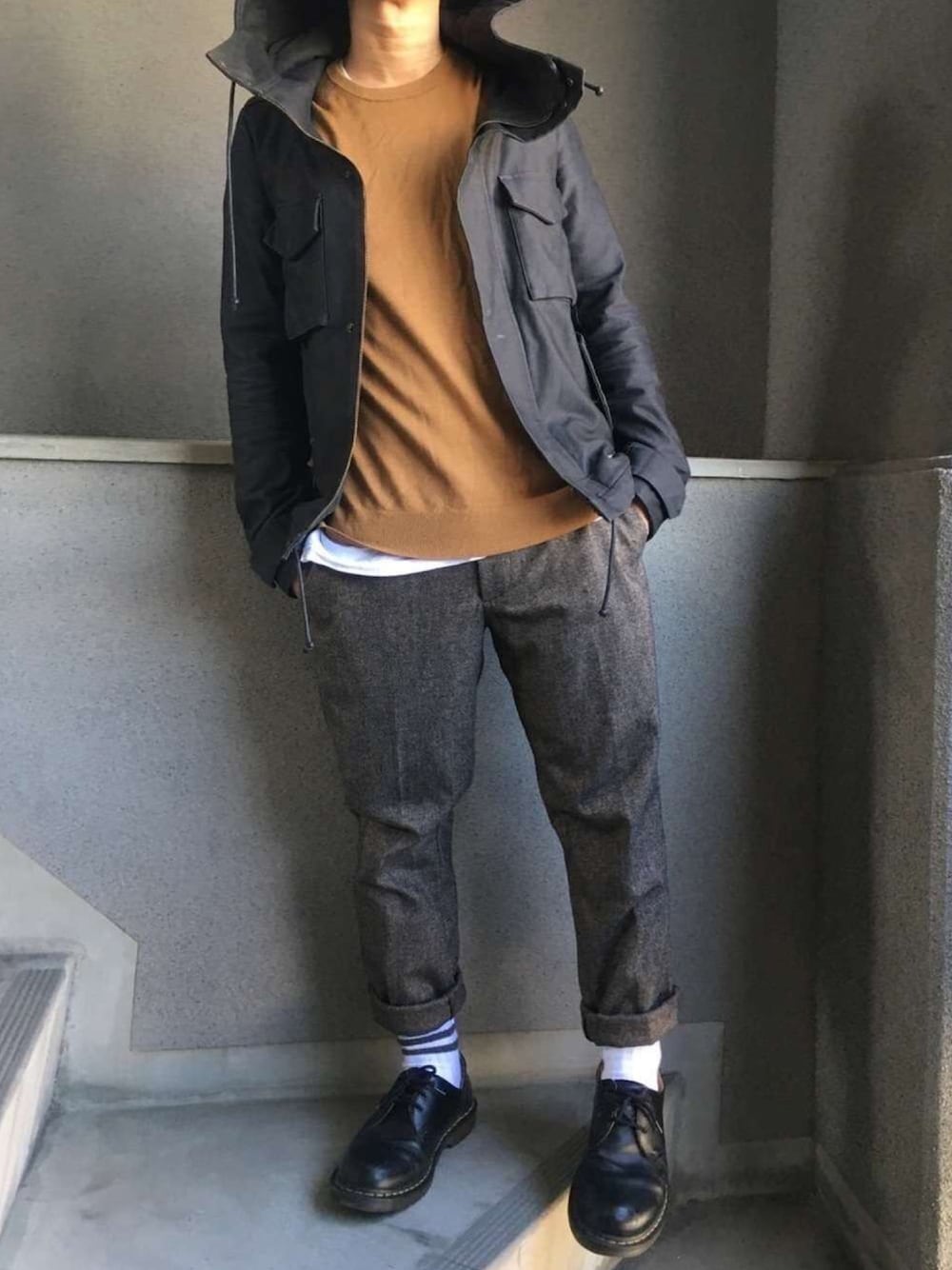 ブラック系のブーツ、ブラウン系のスラックス、ブラック系のミリタリージャケットを着用したメンズの冬コーディネートの1枚目の写真