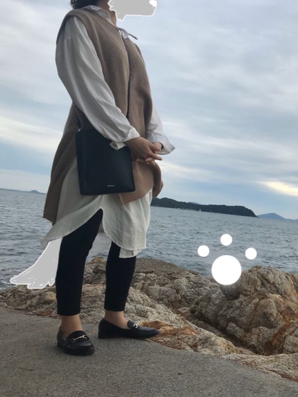 ベージュ系のベスト、ホワイト系のシャツワンピース、ブラック系のローファーを着用したレディースの秋コーディネートの1枚目の写真