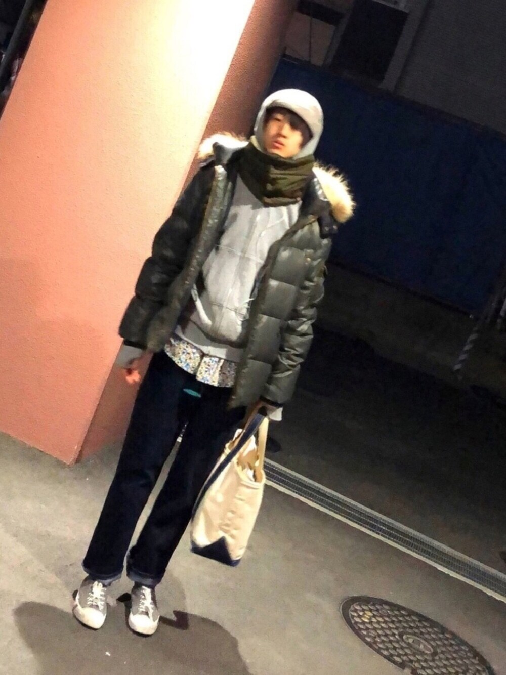 グレー系のスニーカー、ブルー系のデニムパンツ、グレー系のパーカーを着用したメンズの冬コーディネートの1枚目の写真