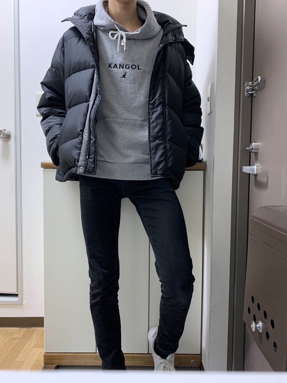 グレー系のパーカー、ブラック系のダウンジャケット/コート、ブラック系のデニムパンツを着用したメンズの冬コーディネートの1枚目の写真