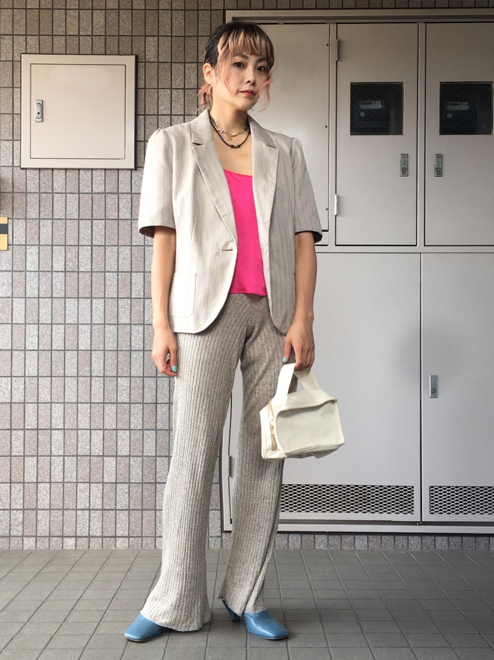 ブラウン系のパンツ、ホワイト系のハンドバッグ、ブルー系のサンダルを着用したレディースの秋コーディネートの1枚目の写真