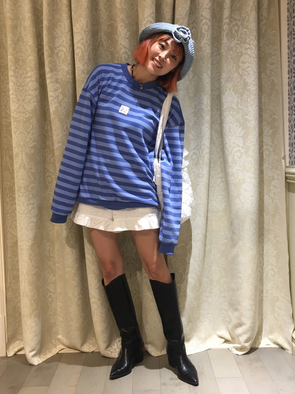 ブルー系のスウェット、ホワイト系のパンツ、ブラック系のブーツを着用したレディースの秋コーディネートの1枚目の写真