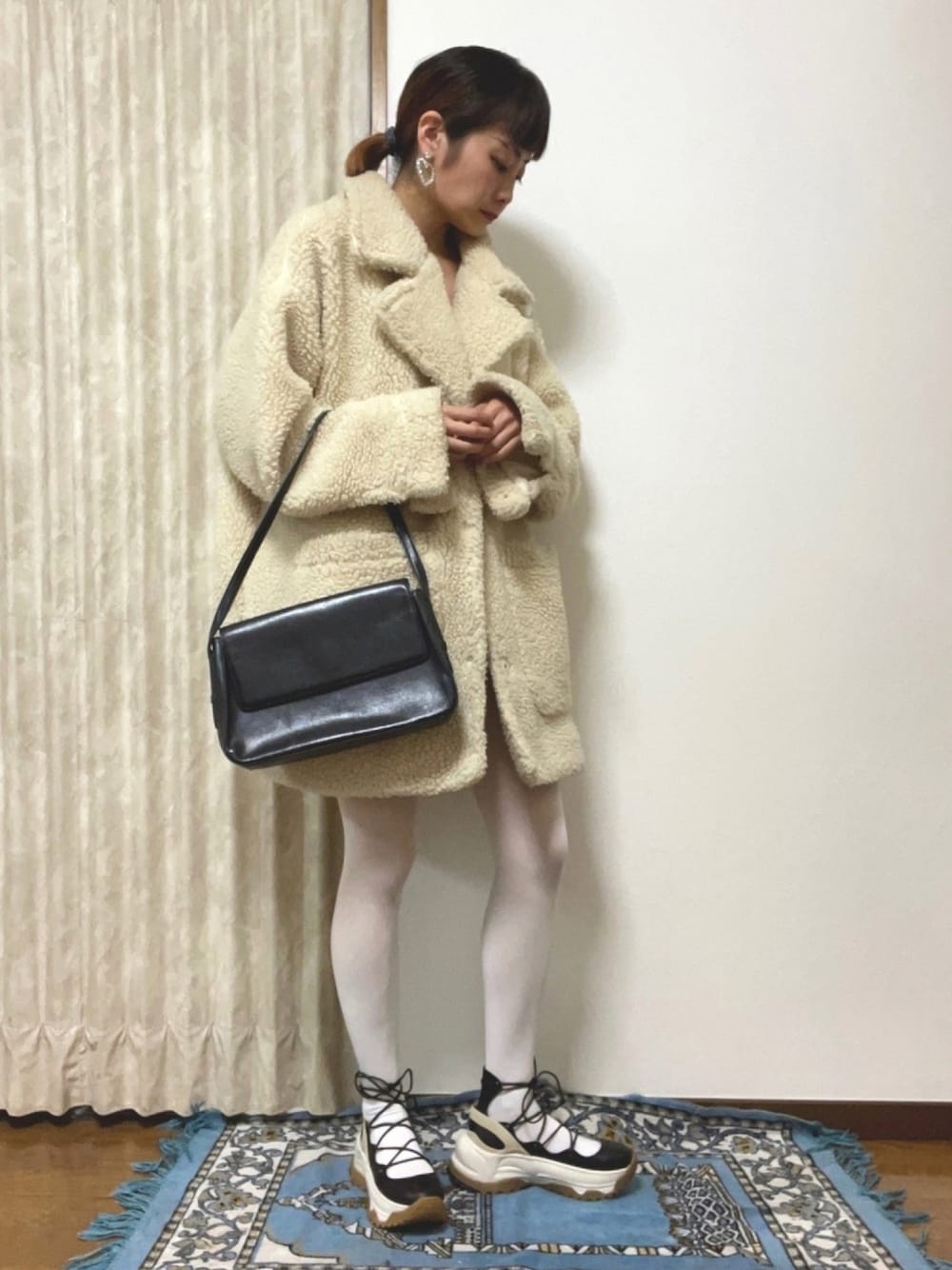 ホワイト系のジャケット/アウター、ブラック系のハンドバッグ、ブラック系のスニーカーを着用したレディースの冬コーディネートの1枚目の写真