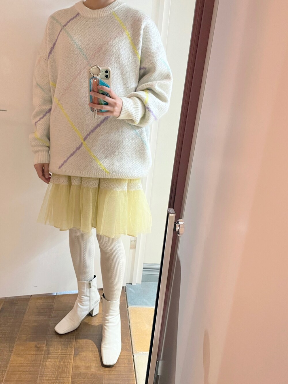 ホワイト系のニット/セーター、イエロー系のスカート、ホワイト系のブーツを着用したレディースの春コーディネートの1枚目の写真