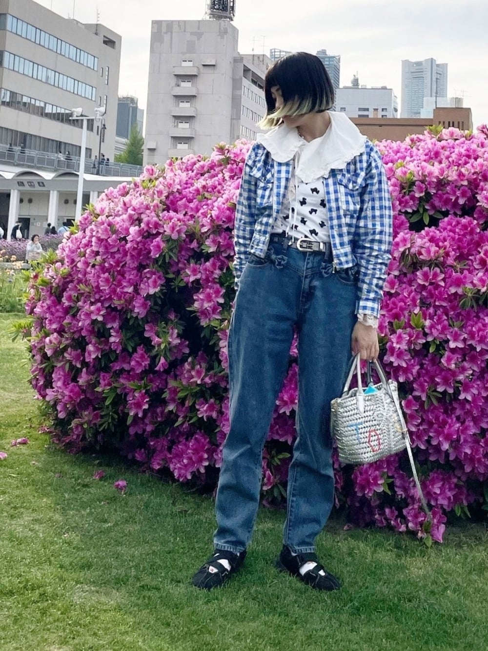 ブルー系のデニムパンツ、ブラック系のスニーカー、シルバー系のハンドバッグを着用したレディースの春コーディネートの1枚目の写真