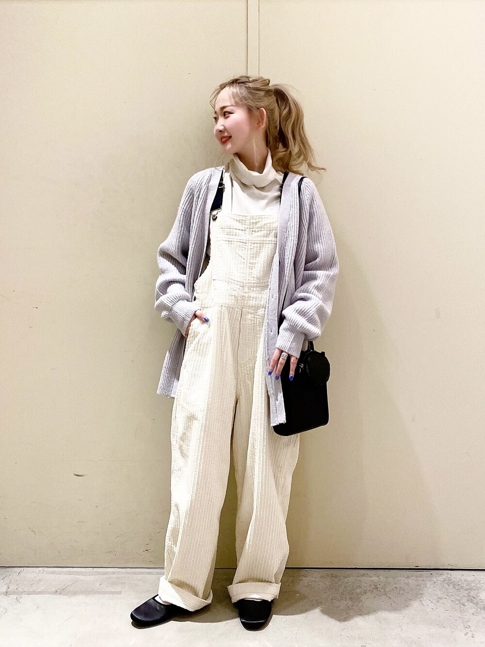 パープル系のカーディガン/ボレロ、ベージュ系のTシャツ/カットソー、ベージュ系のサロペット/オーバーオールを着用したレディースの冬コーディネートの1枚目の写真