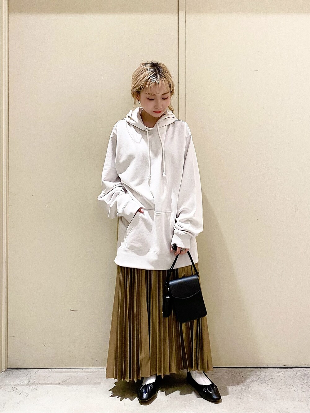 ホワイト系のパーカー、ゴールド系のスカート、ブラック系のショルダーバッグを着用したレディースの春コーディネートの1枚目の写真