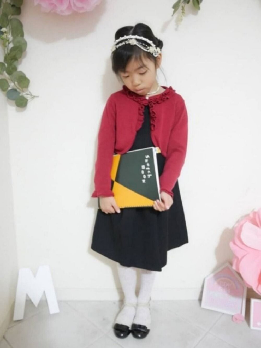 ブラック系のワンピース、レッド系のカーディガン/ボレロ、ブラック系のドレスシューズを着用したキッズの冬コーディネートの1枚目の写真