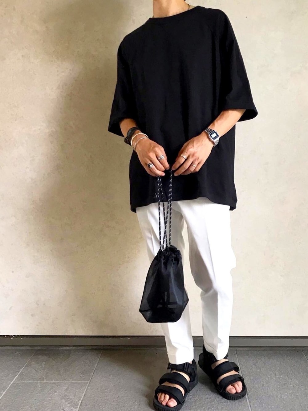 ブラック系のサンダル、ホワイト系のチノパンツ、ブラック系のTシャツ/カットソーを着用したメンズの夏コーディネートの1枚目の写真