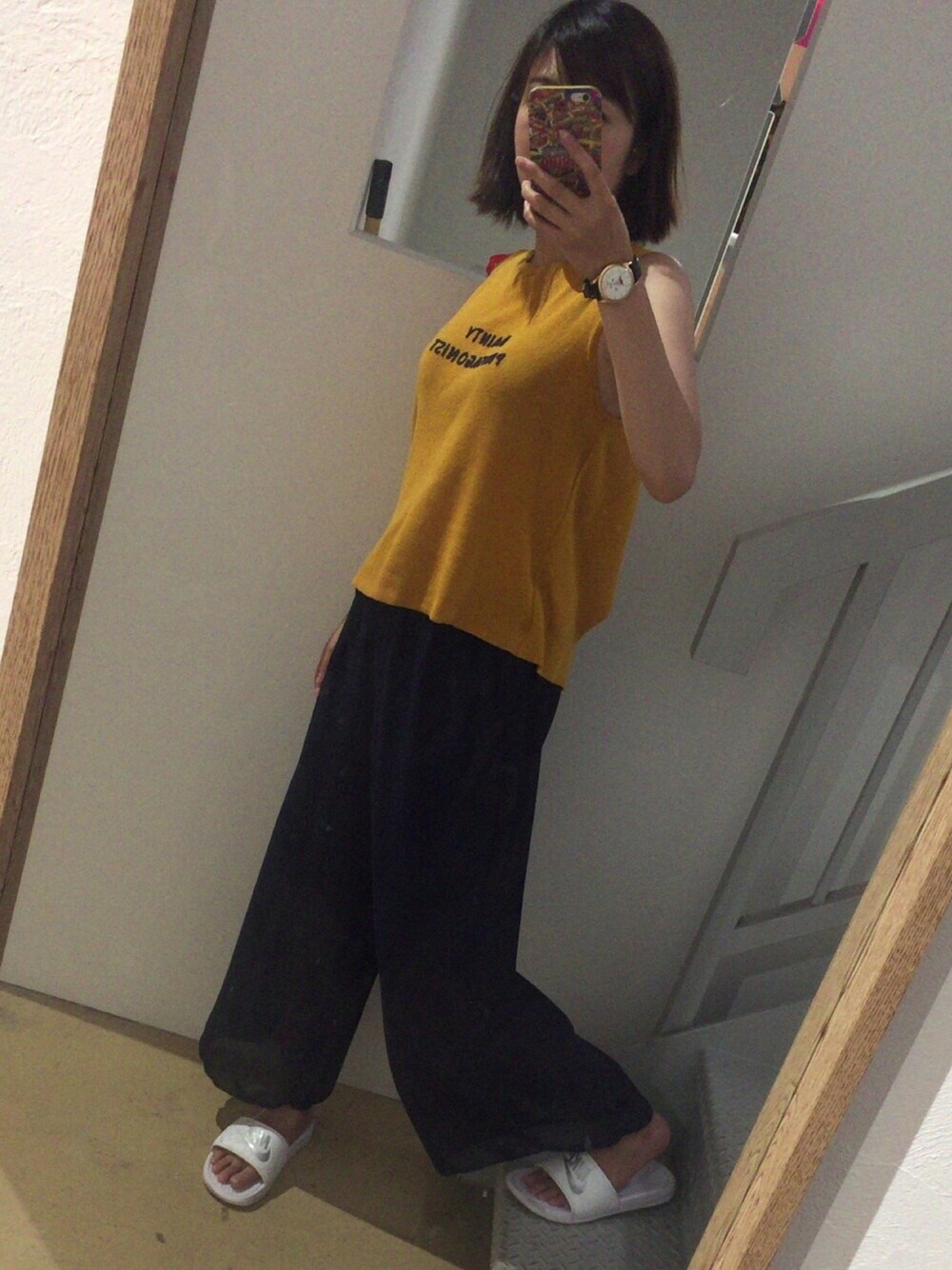 イエロー系のタンクトップ、ブルー系のパンツ、ホワイト系のサンダルを着用したレディースの夏コーディネートの1枚目の写真