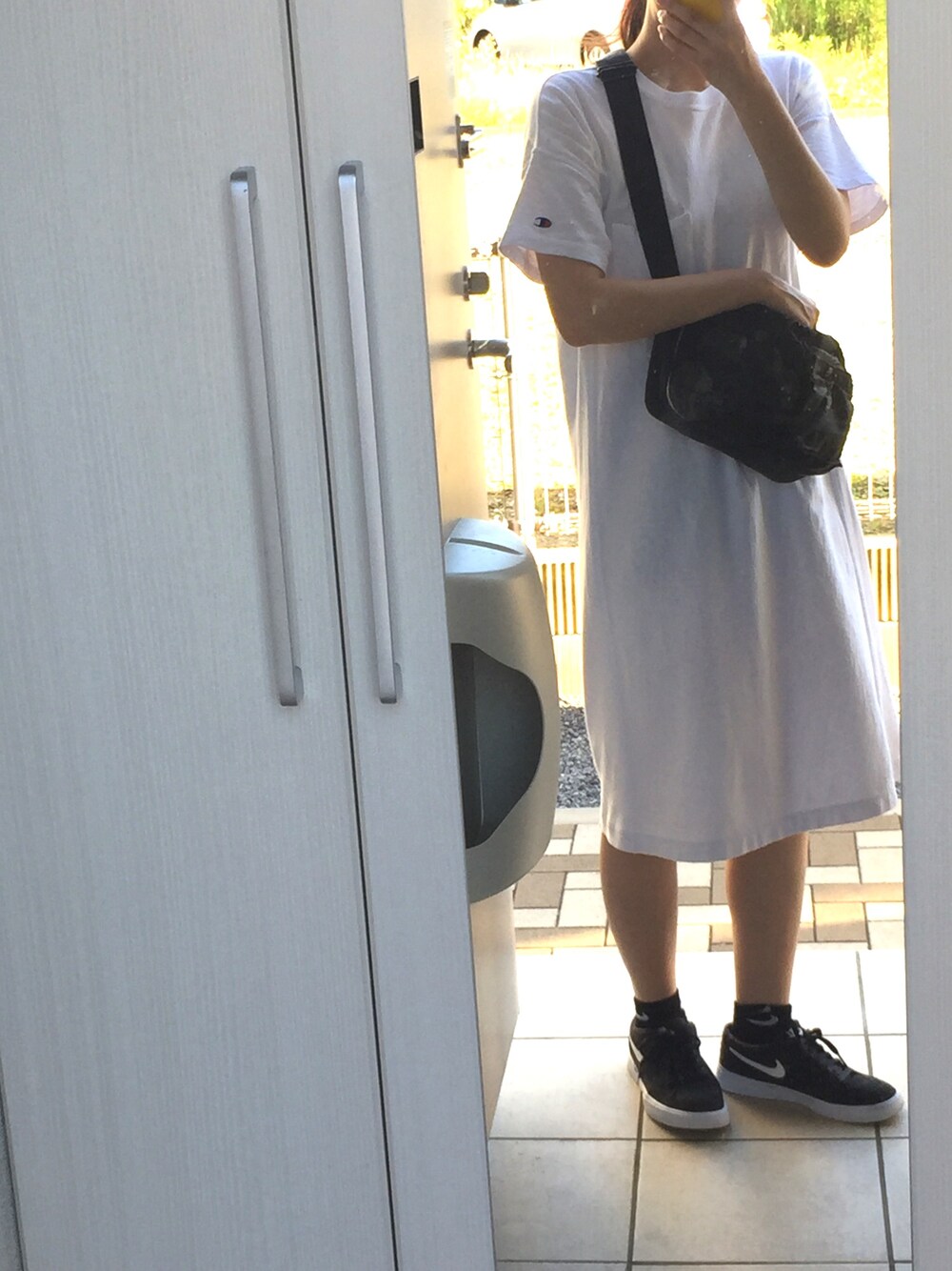 ホワイト系のワンピース、ブラック系のスニーカーを着用したレディースの夏コーディネートの1枚目の写真