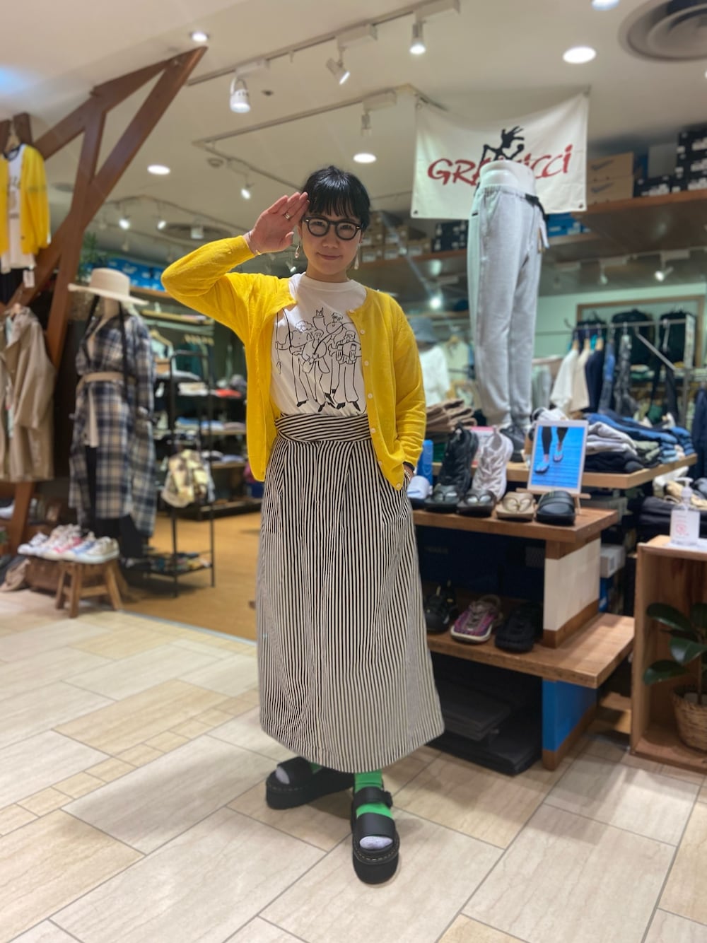 「春、カジュアル、スカート、プリントT、ドクターマーチン、サンダルに靴下、サンダル、BEAVER、BEAVER名古屋、厚底シューズ」｜「MANASTASHのMANASTASH/マナスタッシュ　リネン　UVカットカーディガン（カーディガン/ボレロ、イエロー系）」を使った、小林さん（レディース・155cm）の春コーディネートの1枚目の写真