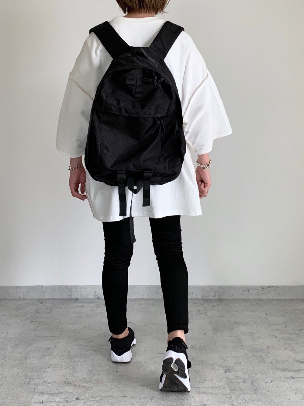 ブラック系のバックパック/リュック、ホワイト系のTシャツ/カットソー、ブラック系のスニーカーを着用したレディースの夏コーディネートの1枚目の写真
