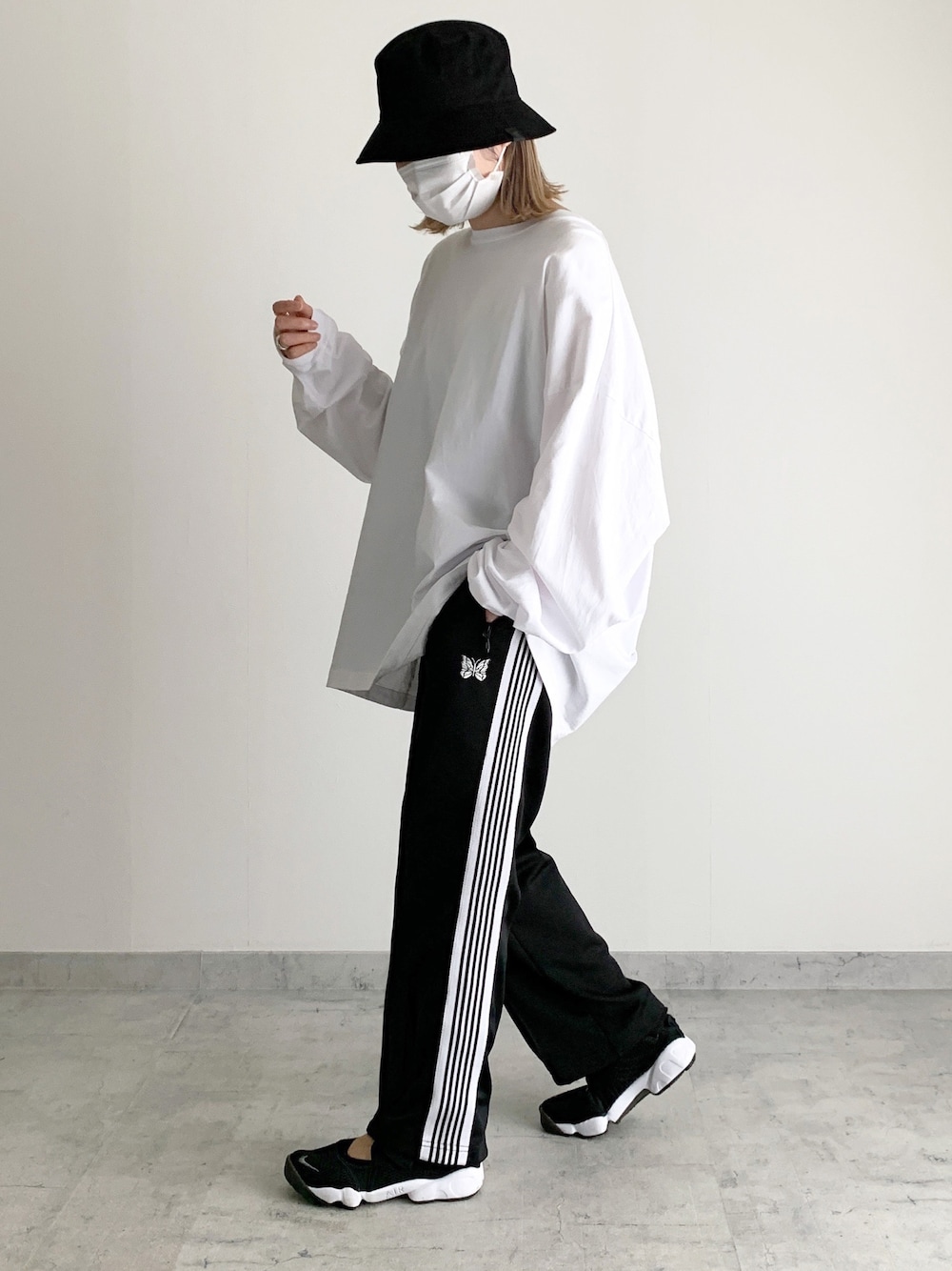 ホワイト系のTシャツ/カットソー、ブラック系のパンツ、ブラック系のスニーカーを着用したレディースの春コーディネートの1枚目の写真