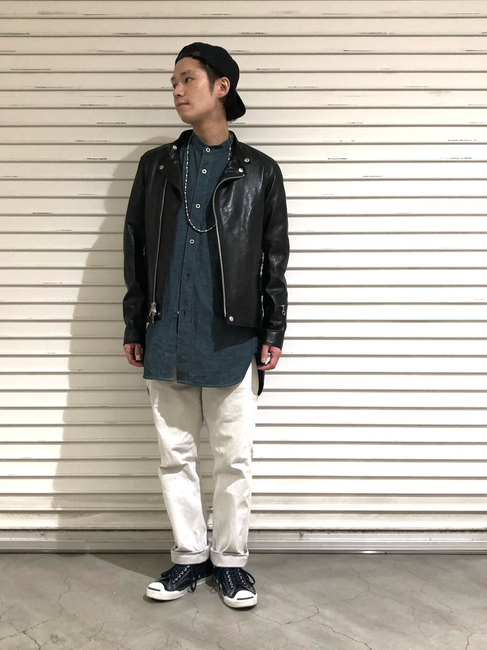 ブラック系のライダースジャケット、ブラック系のキャップを着用したメンズの春コーディネートの1枚目の写真