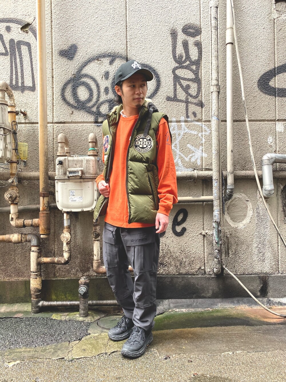 オレンジ系のTシャツ/カットソー、グリーン系のジャケット/アウター、グレー系のその他パンツを着用したメンズの秋コーディネートの1枚目の写真
