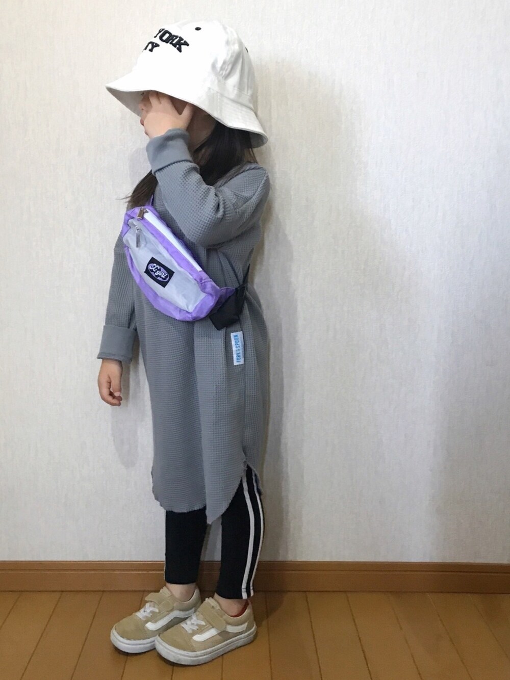 グレー系のワンピース、ベージュ系のスニーカー、ホワイト系のハットを着用したキッズの春コーディネートの1枚目の写真