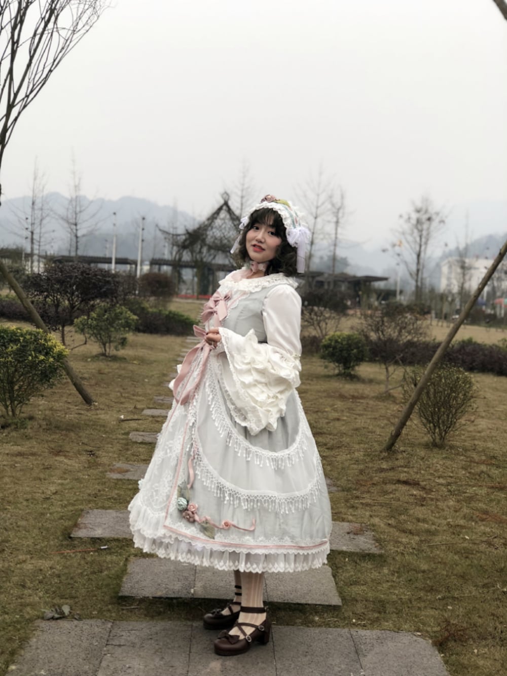 グリーン系のジャンパースカートを着用したレディースの冬コーディネートの1枚目の写真