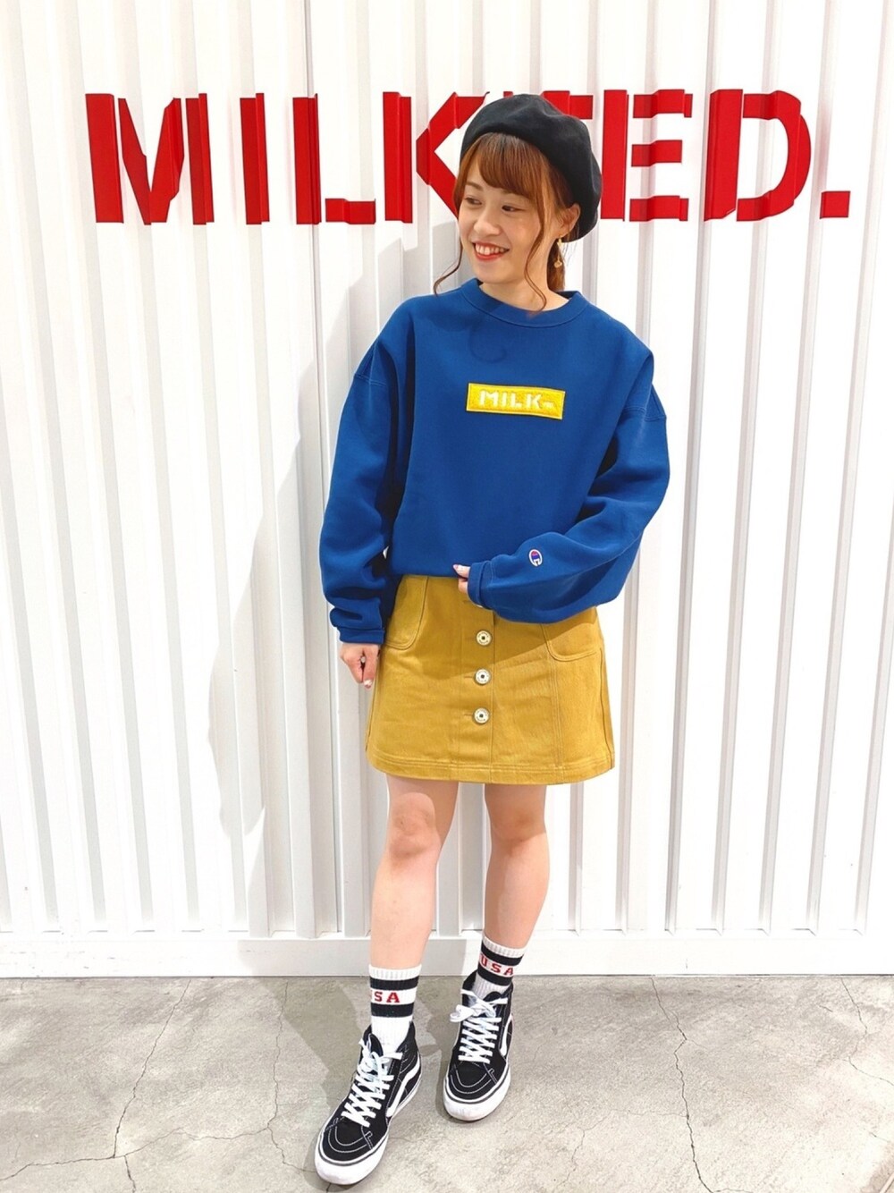 ブルー系のスウェット、ベージュ系のスカート、ブラック系のスニーカーを着用したレディースの秋コーディネートの1枚目の写真