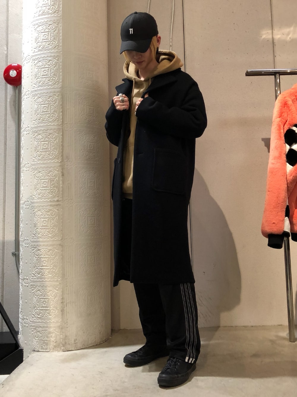 ブラック系のチェスターコート、ブラック系のその他パンツ、ベージュ系のパーカーを着用したメンズの冬コーディネートの1枚目の写真