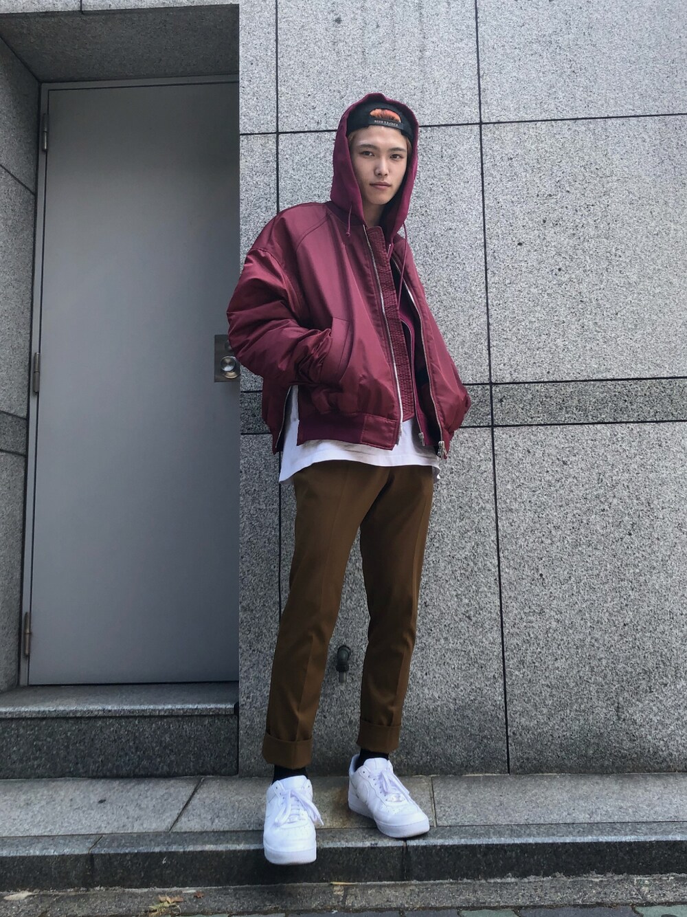 レッド系のブルゾン、ブラウン系のスラックス、ブラック系のキャップを着用したメンズの夏コーディネートの1枚目の写真