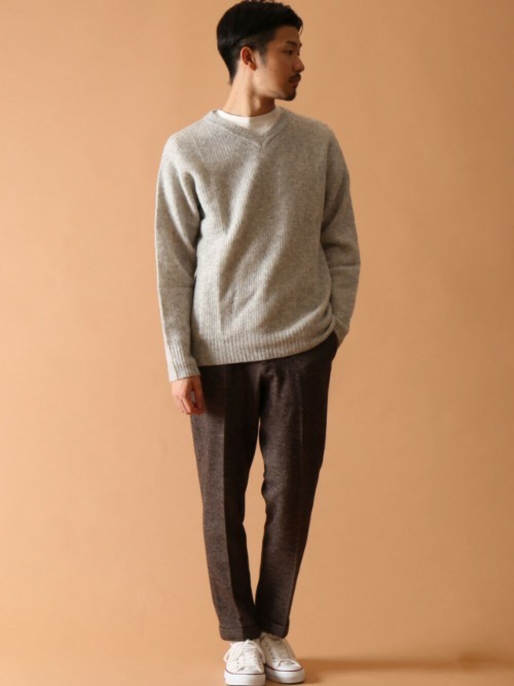 グレー系のニット/セーター、ホワイト系のTシャツ/カットソー、ホワイト系のスニーカーを着用したメンズの冬コーディネートの1枚目の写真