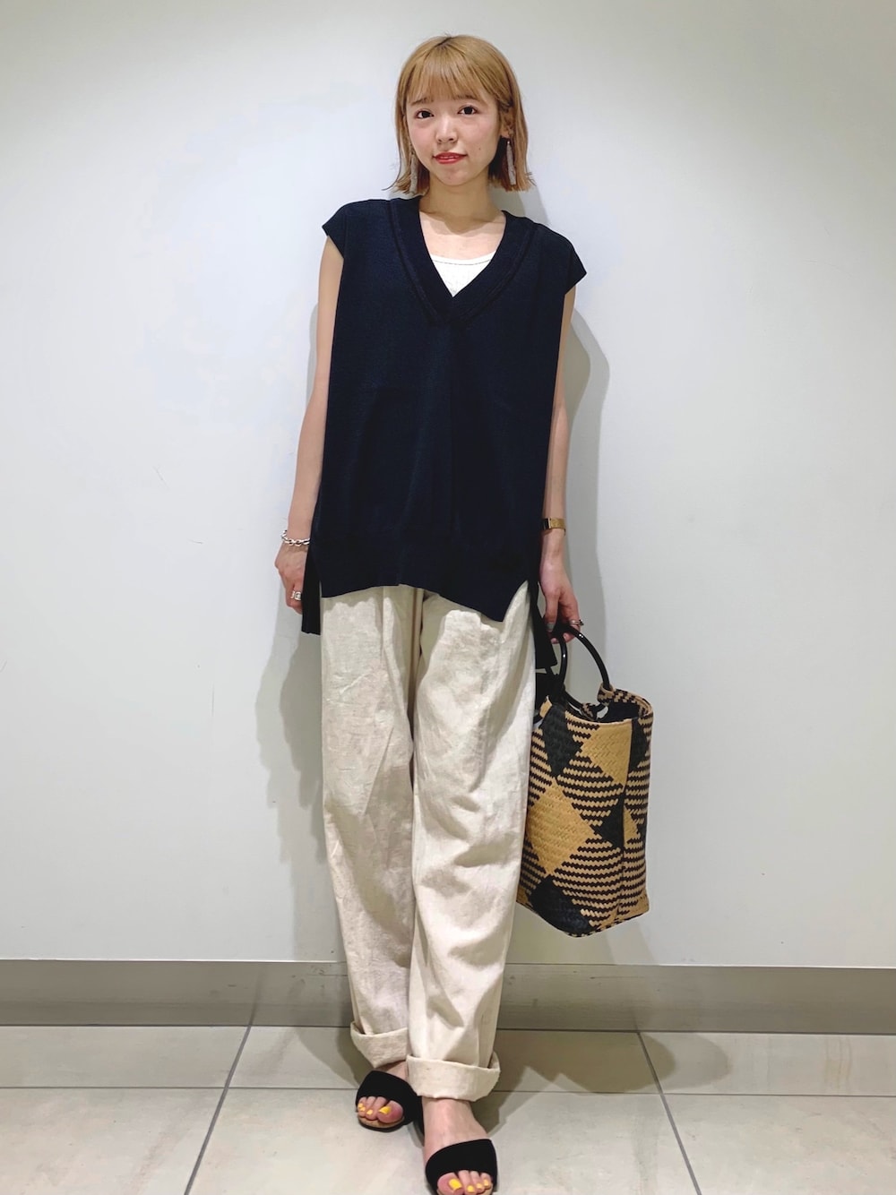 ブラック系のニット/セーター、ホワイト系のデニムパンツ、ブラック系のトートバッグを着用したレディースの春コーディネートの1枚目の写真