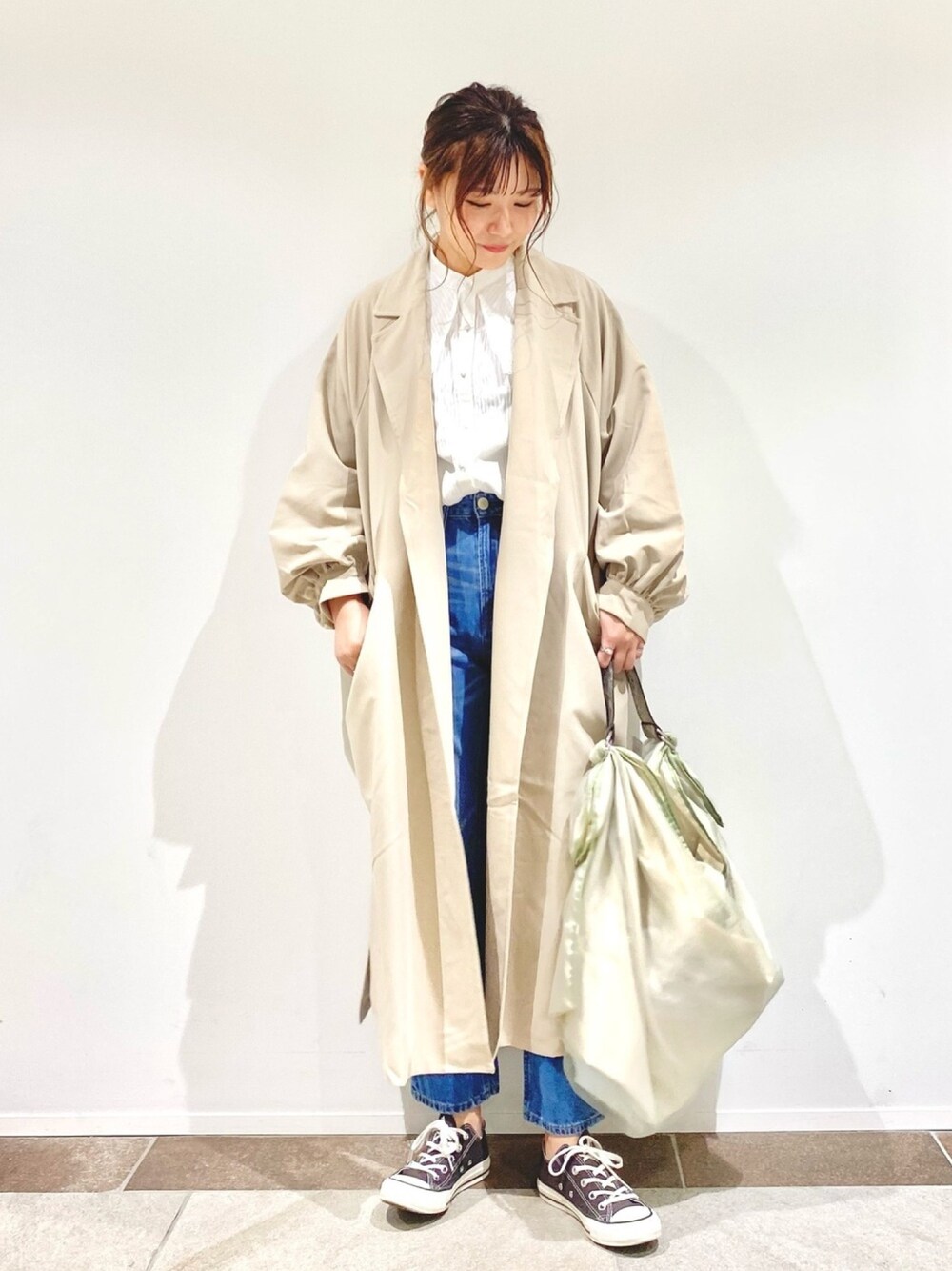 ベージュ系のトレンチコート、グリーン系のトートバッグ、ホワイト系のシャツ/ブラウスを着用したレディースの春コーディネートの1枚目の写真