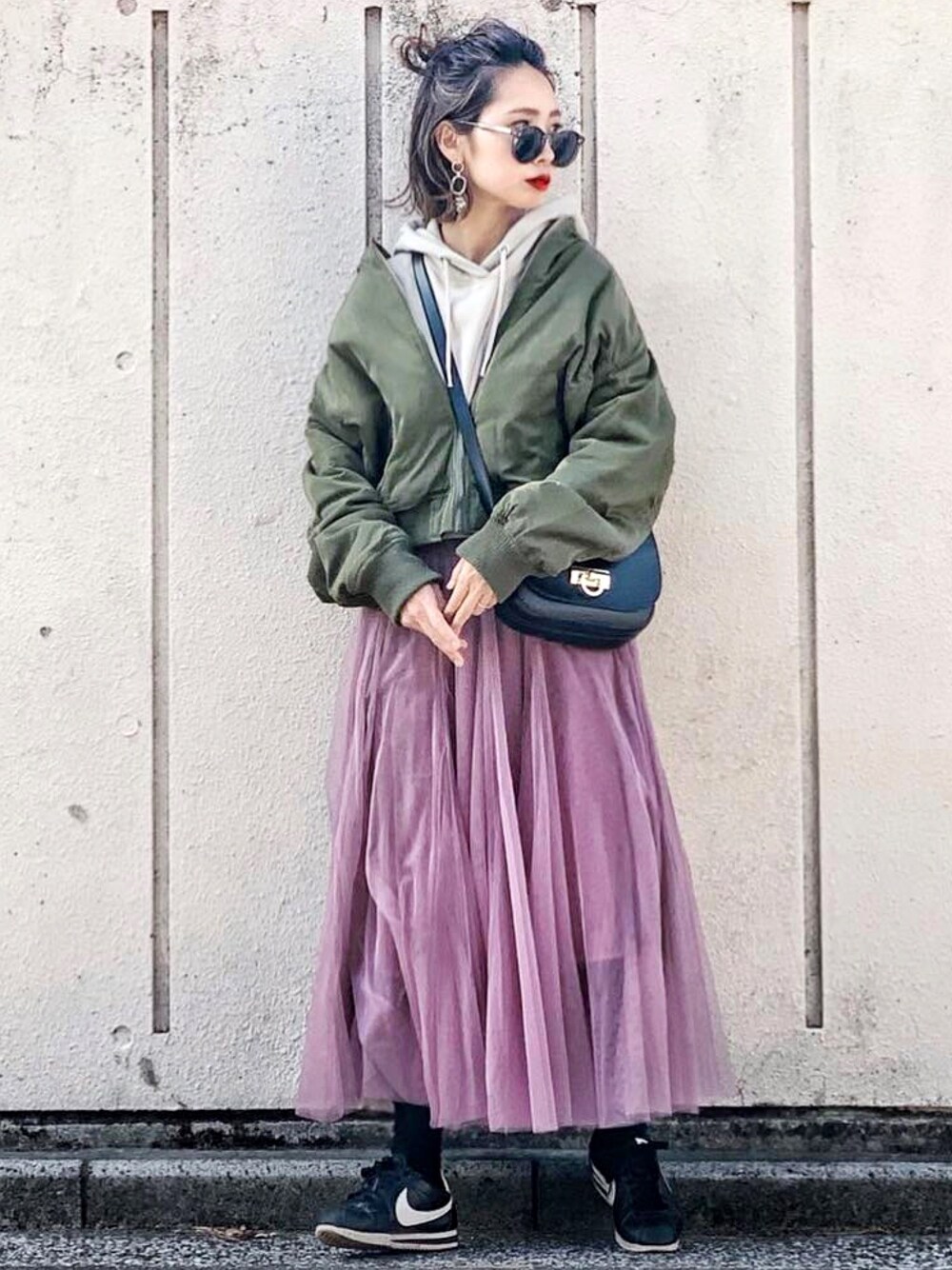 ピンク系のスカート、グリーン系のMA-1、ブラック系のショルダーバッグを着用したレディースの冬コーディネートの1枚目の写真