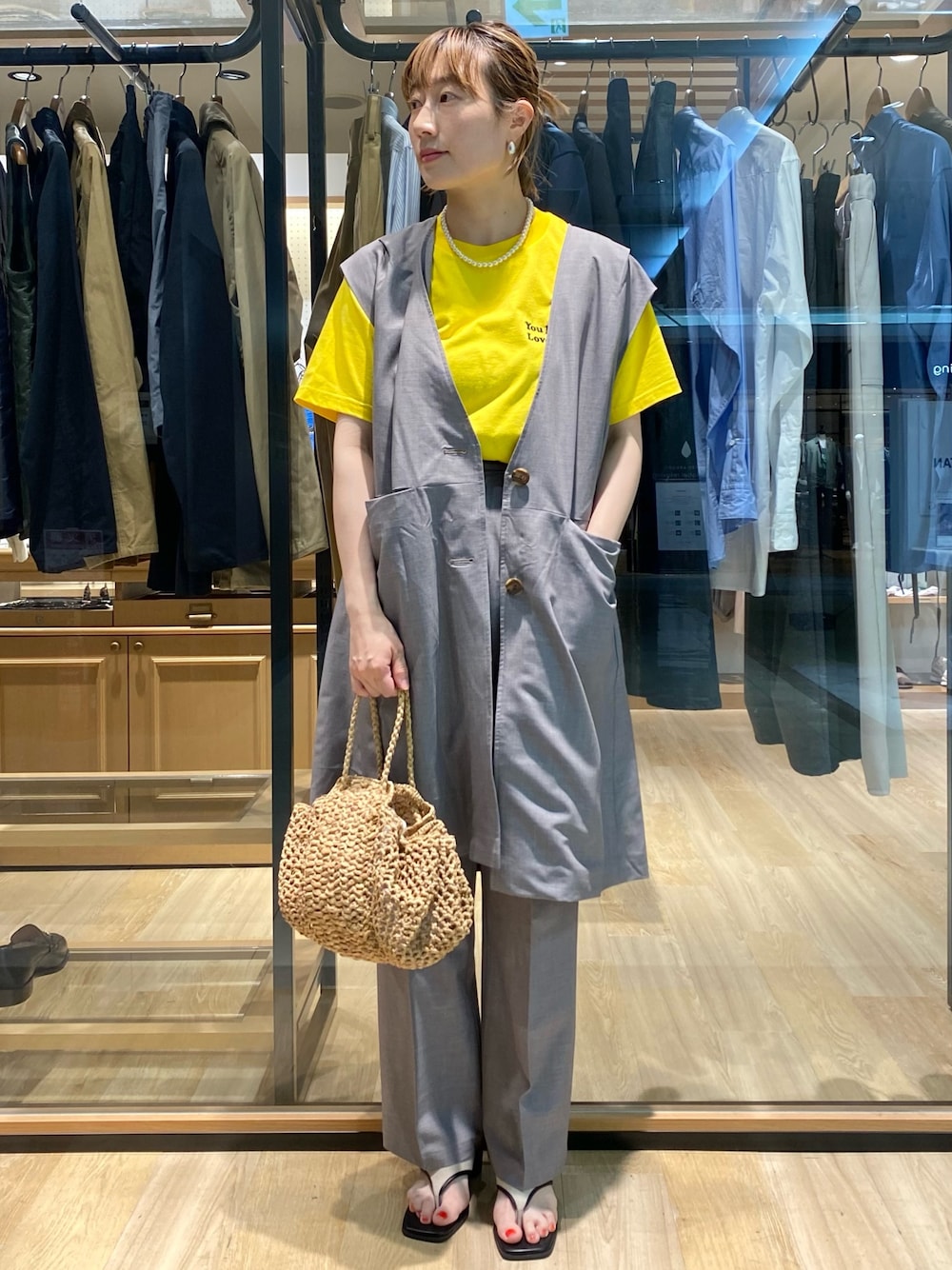 グレー系のベスト、イエロー系のTシャツ/カットソー、グレー系のスラックスを着用したレディースの夏コーディネートの1枚目の写真