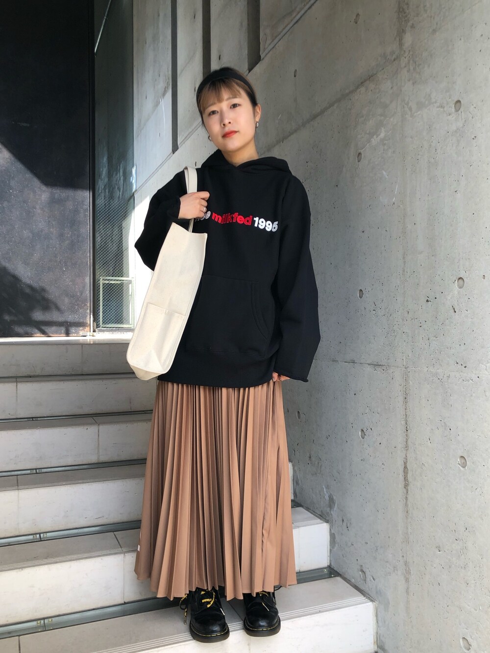 ブラック系のパーカー、ベージュ系のスカート、レッド系のトートバッグを着用したレディースの冬コーディネートの1枚目の写真