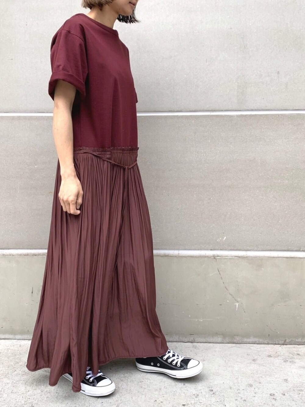 レッド系のワンピース、ブラック系のスニーカーを着用したレディースの冬コーディネートの1枚目の写真