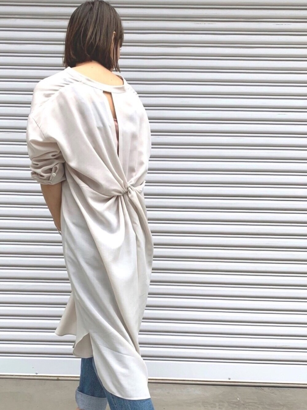 ベージュ系のワンピース、ピンク系のTシャツ/カットソー、ブルー系のデニムパンツを着用したレディースの春コーディネートの1枚目の写真