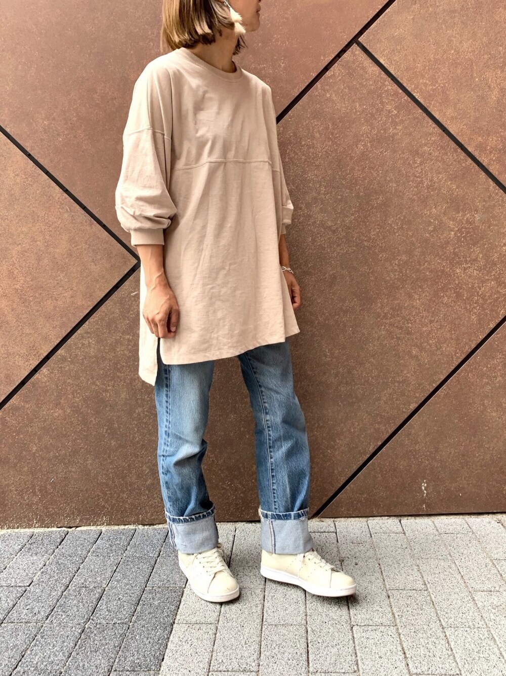 ベージュ系のTシャツ/カットソー、ブルー系のデニムパンツ、ベージュ系のスニーカーを着用したレディースの春コーディネートの1枚目の写真