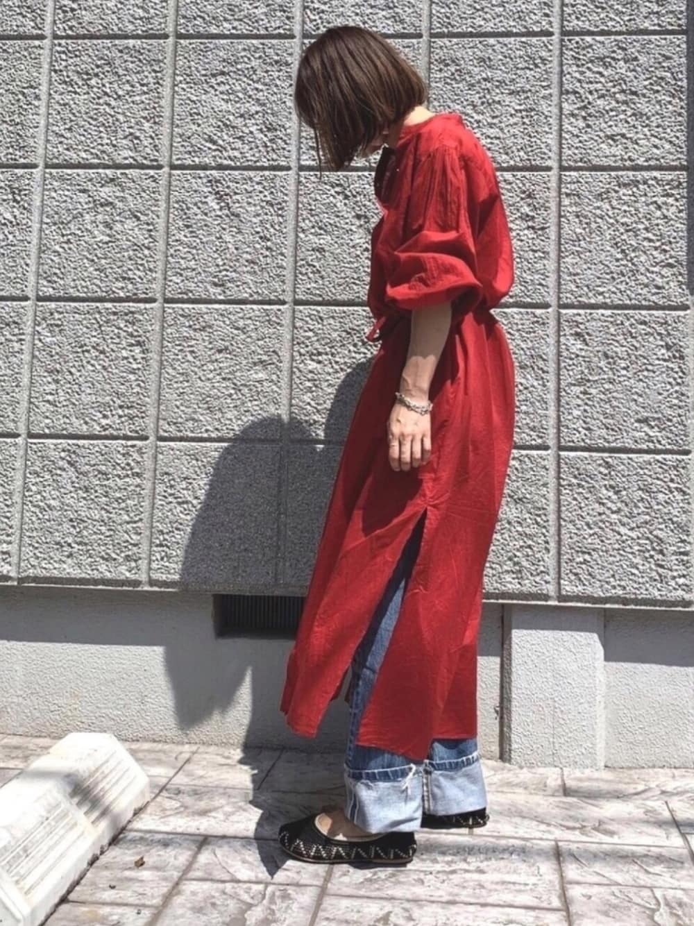 レッド系のシャツワンピース、ブルー系のデニムパンツを着用したレディースの夏コーディネートの1枚目の写真