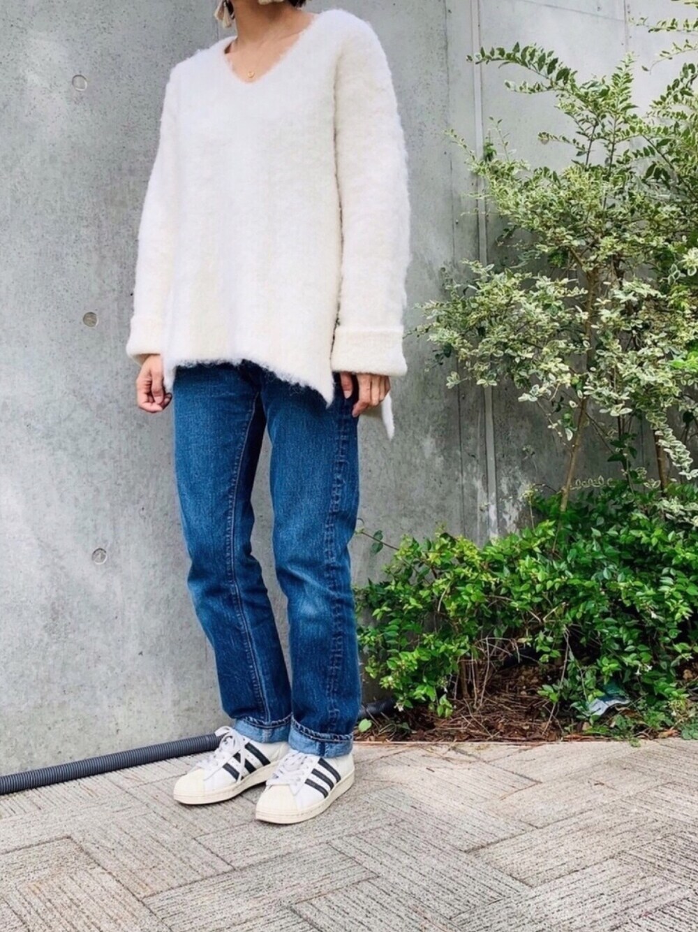 ホワイト系のニット/セーター、ブルー系のデニムパンツ、ホワイト系のスニーカーを着用したレディースの秋コーディネートの1枚目の写真