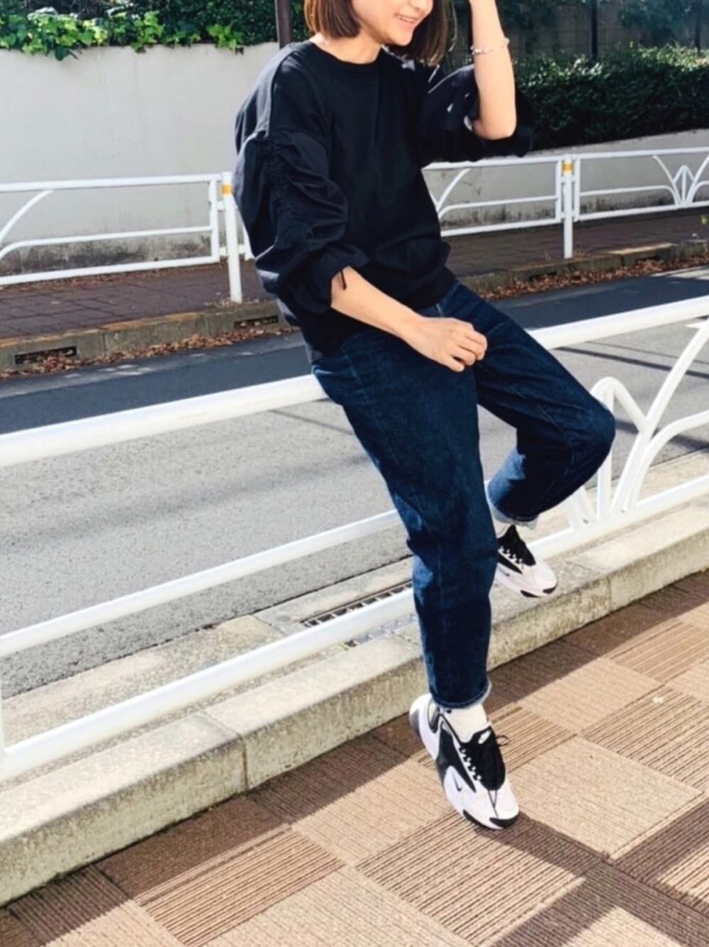 ブラック系のニット/セーター、ブルー系のデニムパンツ、ホワイト系のスニーカーを着用したレディースの冬コーディネートの1枚目の写真