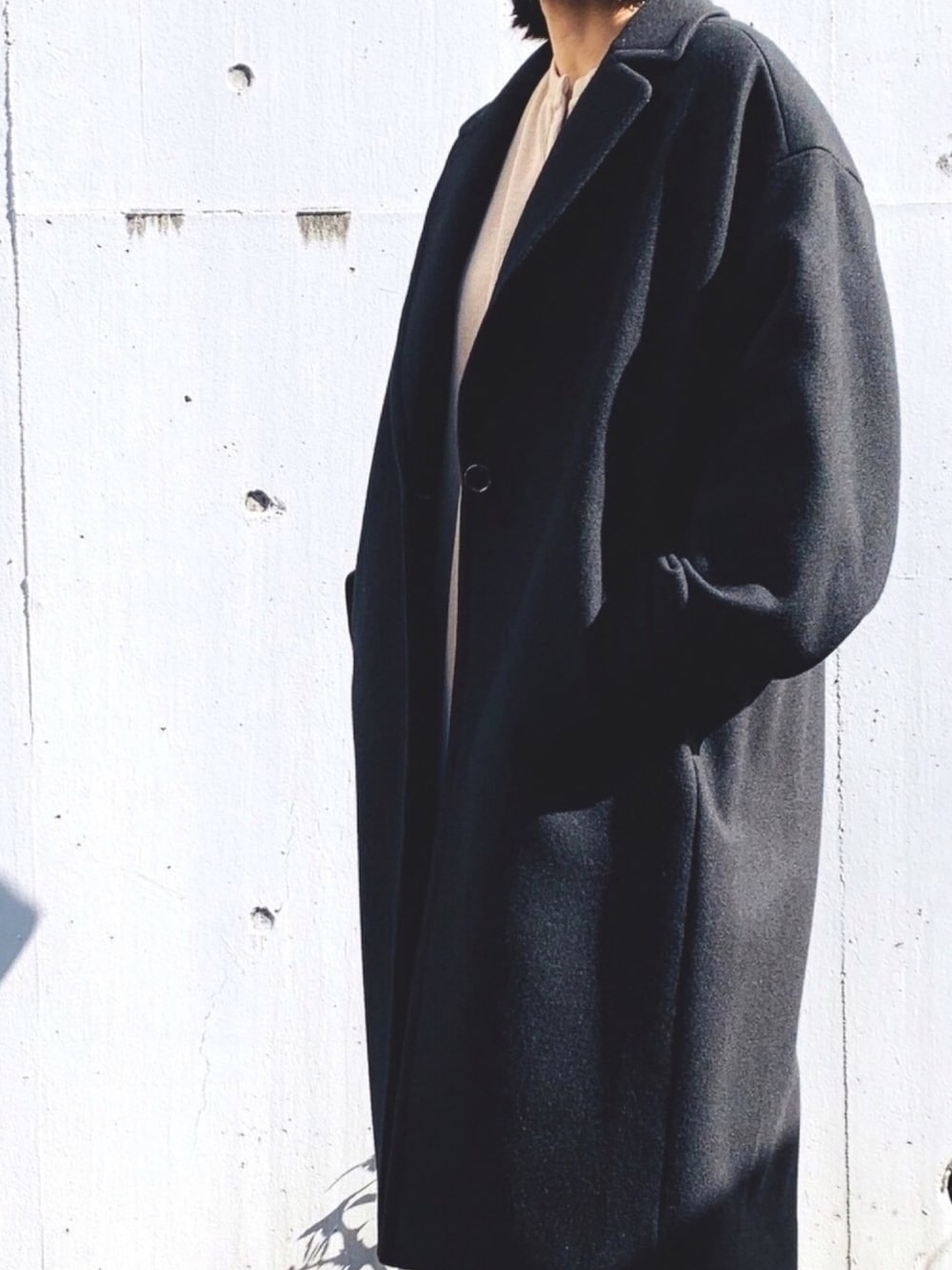 ブラック系のチェスターコート、ベージュ系のワンピースを着用したレディースの秋コーディネートの1枚目の写真